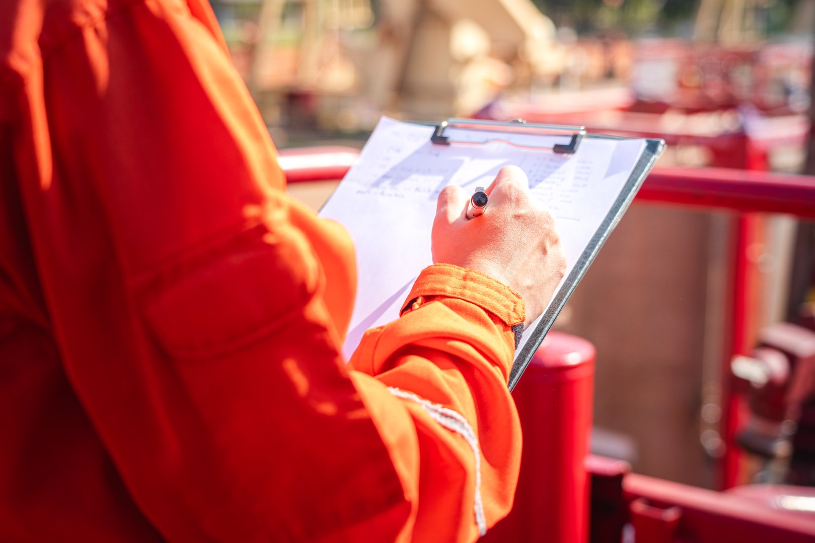 Action of safety officer is writing and check on checklist document during safety audit and inspection at drilling site operation. Industrial expertise occupation working scene.
