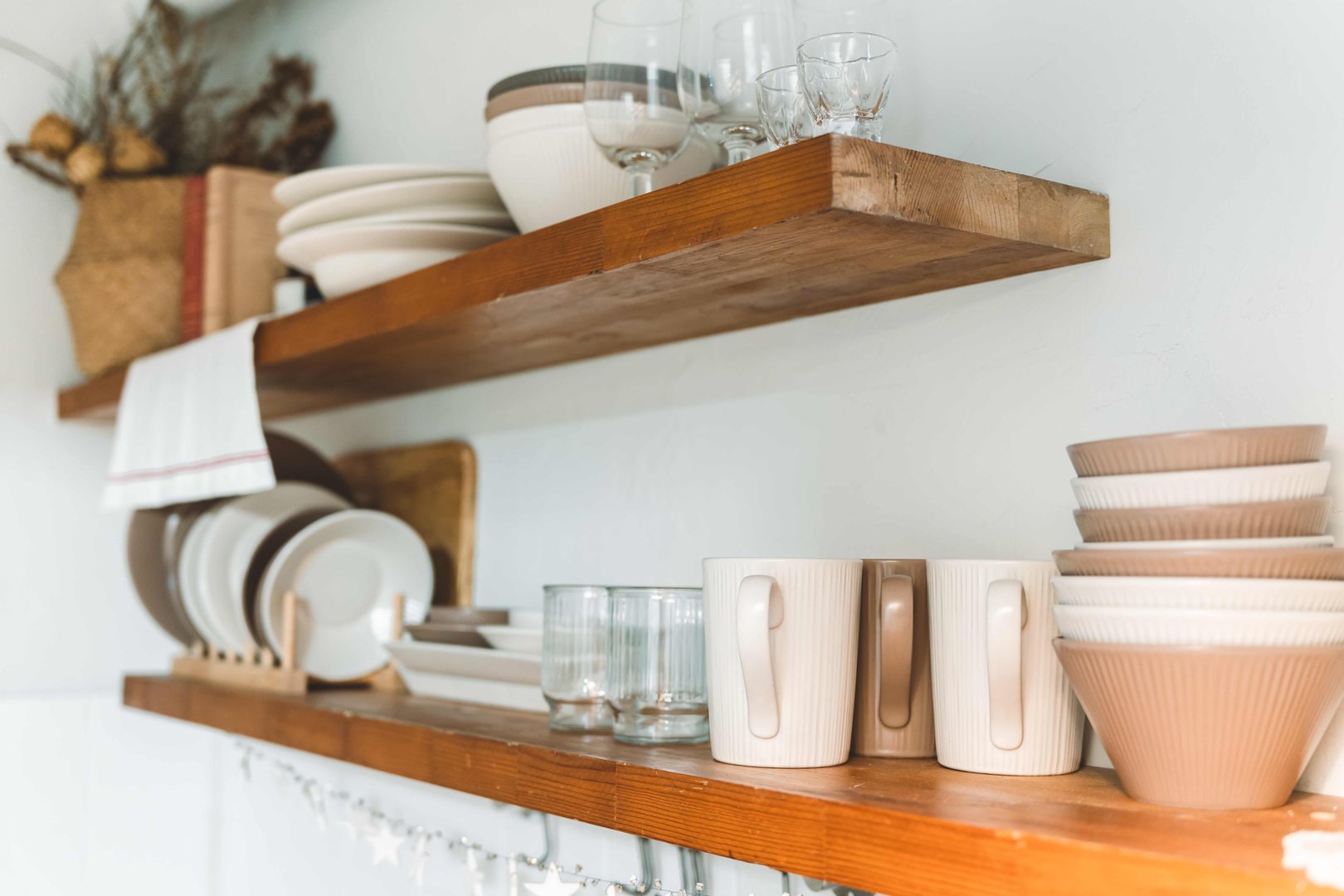 Wooden shelf with Glass, coffee cup, plate, bowl various cookware and decoration in kitchen. Hanging storage. Organization kitchen room concept