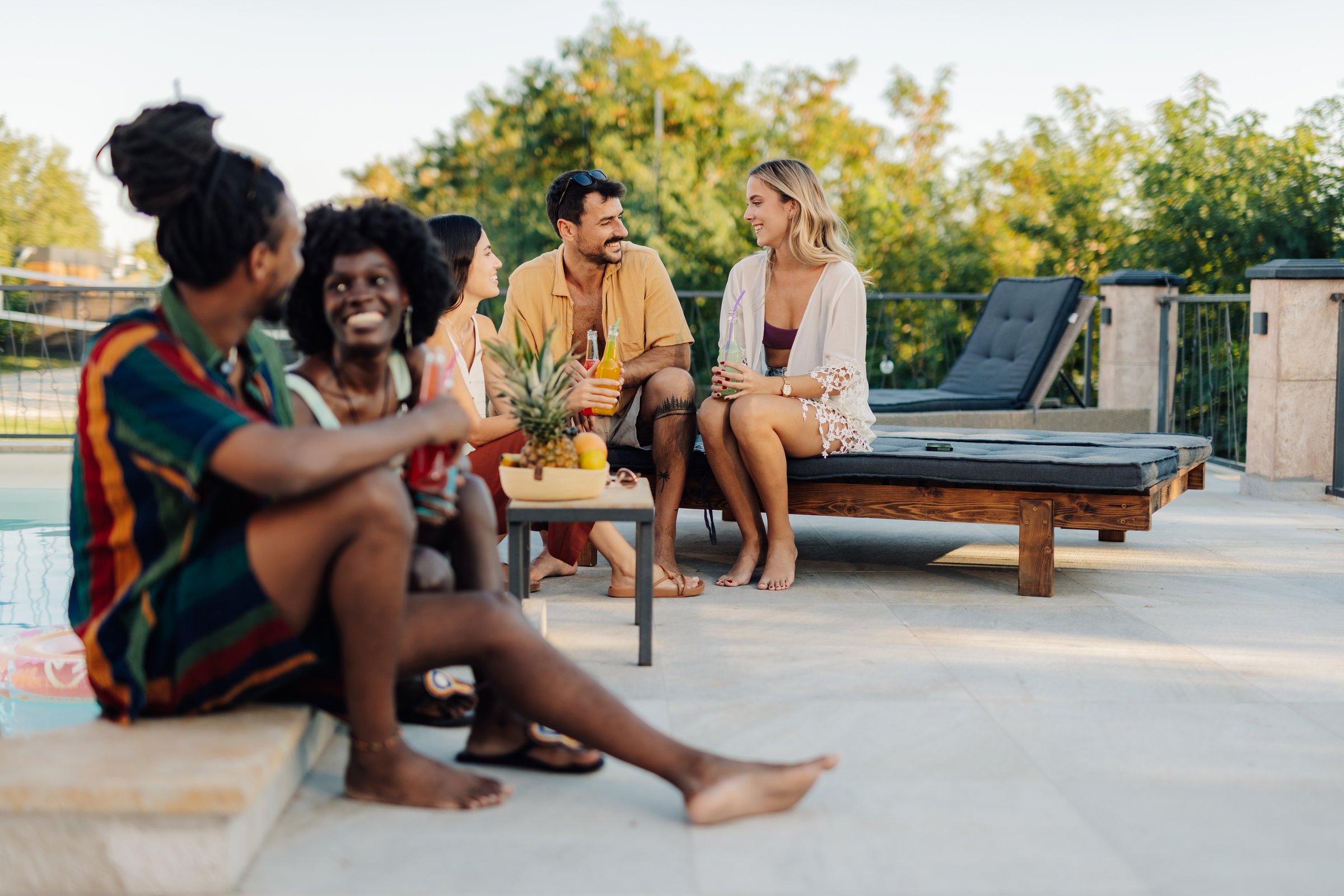 Friends enjoying drinks by the swimming pool during summer vacation