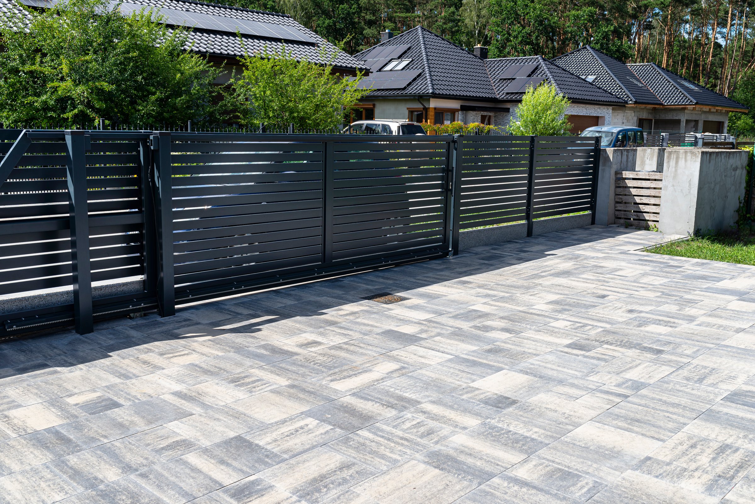 Modern panel fencing in anthracite color, visible sliding gate to the garage as well as a handle and a lock.
