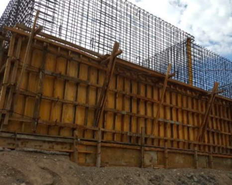 Construction site with a wooden formwork structure and steel rebar grid for a future concrete wall.