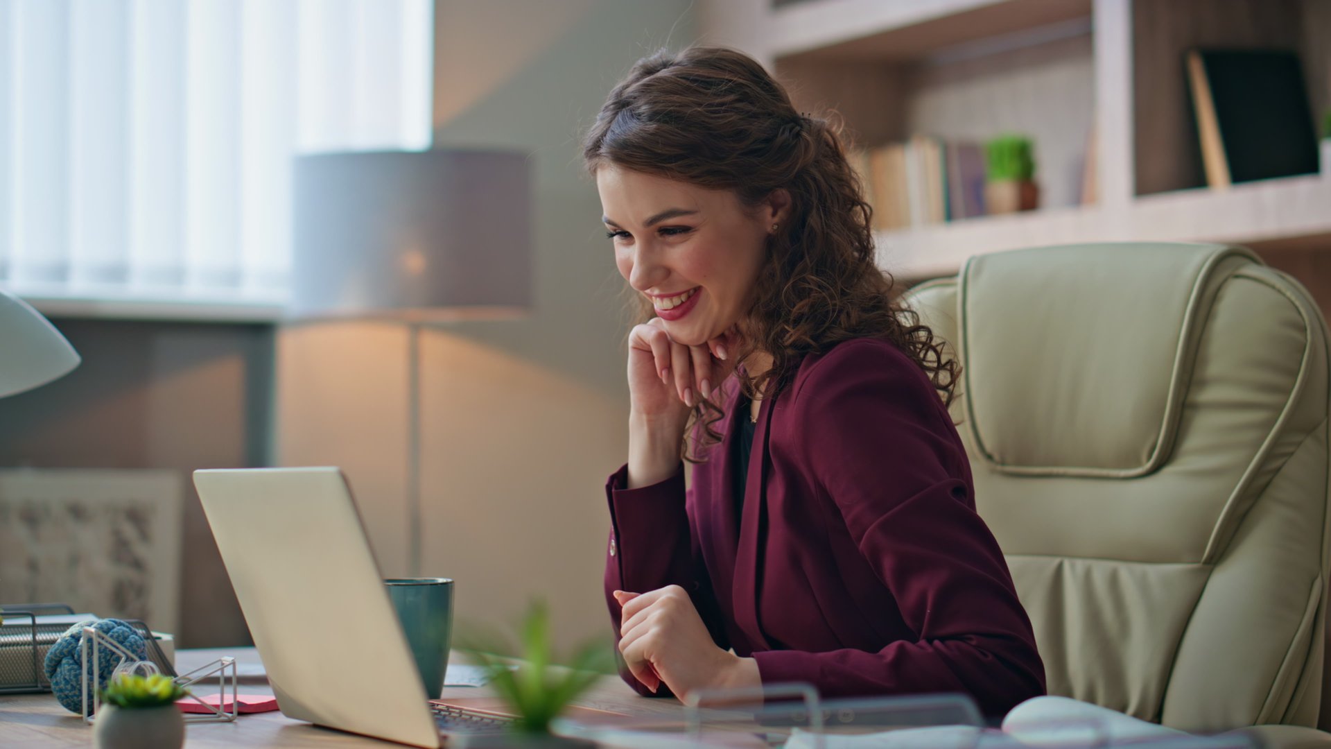 Friendly manager greeting video call in company office closeup. Smiling woman manager talk online waving hand on virtual conference. Joyful businesswoman holding papers consulting client on videocall.