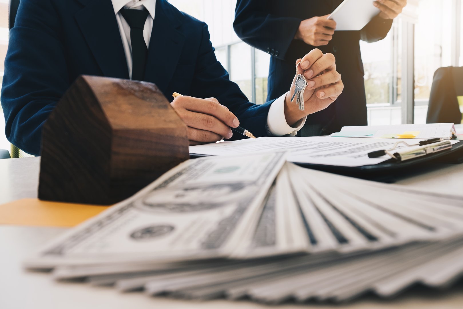 real estate agent holding house key to his client during sign contract agreement in office, concept for real estate, moving home or renting property