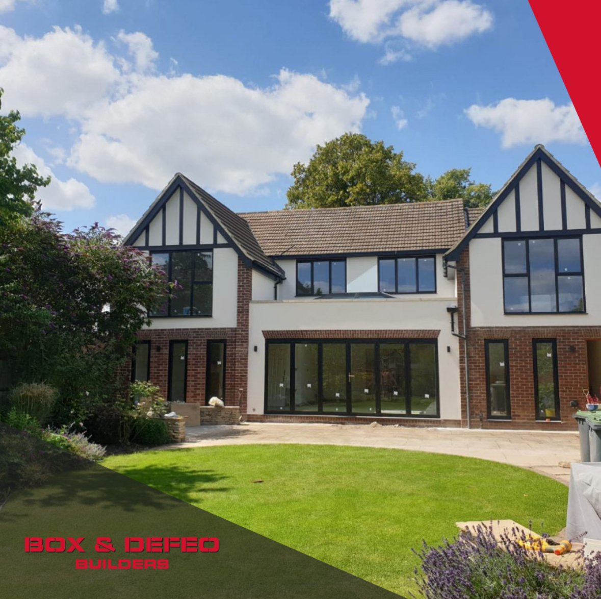 Modern luxury home exterior with large windows, stone facade, and spacious driveway at sunset.