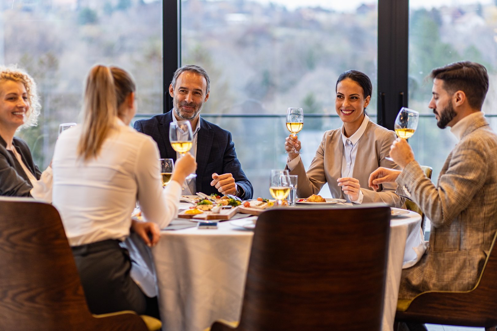 Smiling coworkers in restaurant talking during business lunch.