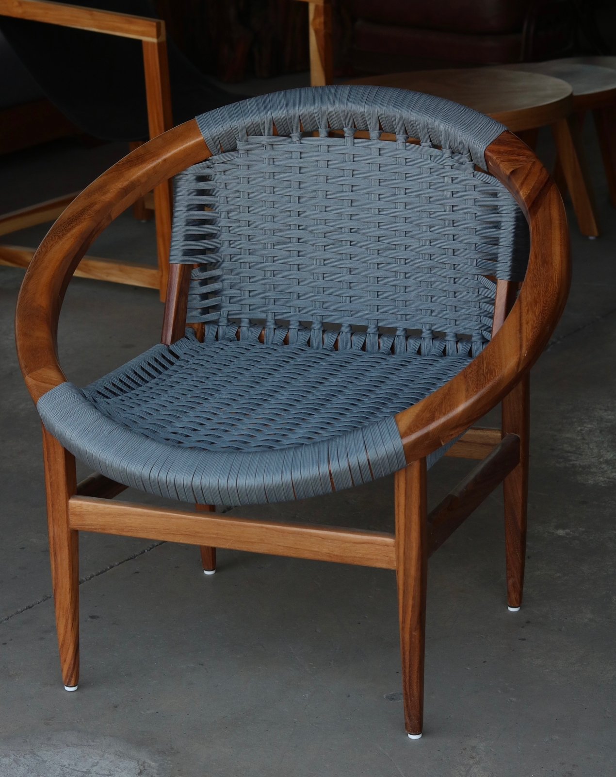 Butaca de diseño envolvente con aro circular de madera y asiento-respaldo tejido en cordón de nailon náutico