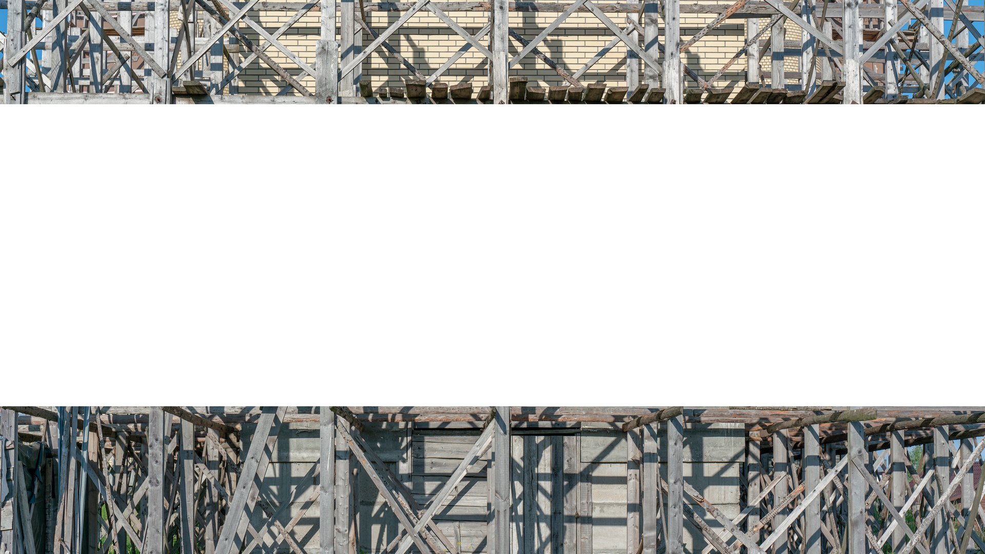 Blank white banner on wooden scaffolding at construction site. Empty space for advertisement on industrial framework background.