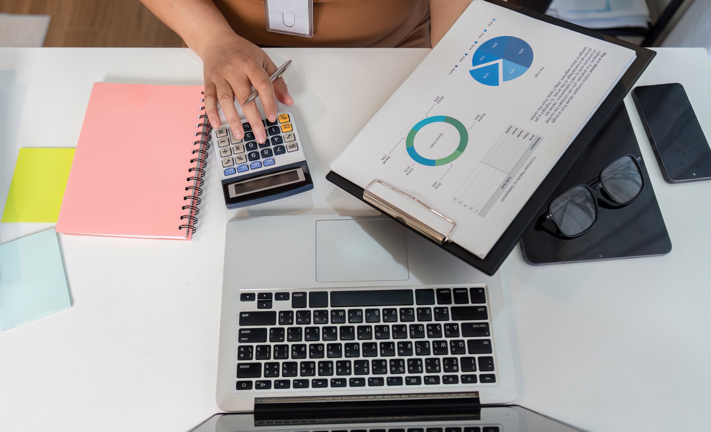 A detailed view of a female accountant working diligently on financial documents, showcasing professionalism and focus in a modern office environment.