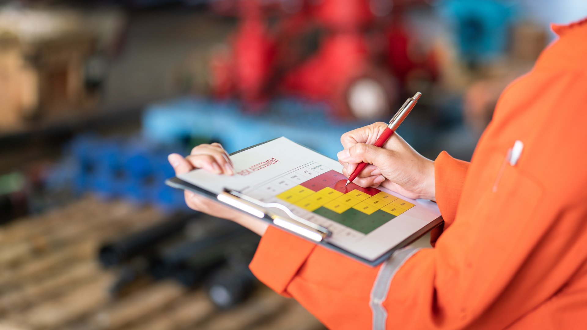 Action of a person is using ballpoint pen to marking on the risk assessment matrix table at "High risk" level. Industrial or business working action scene photo. Close-up and selective focus.