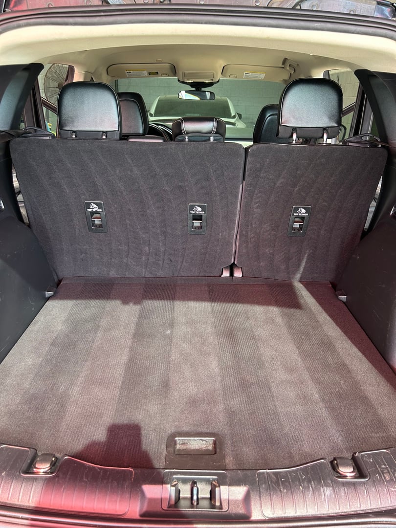 Interior view of an SUV's open trunk with rear seats in upright position, showing spacious cargo area.
