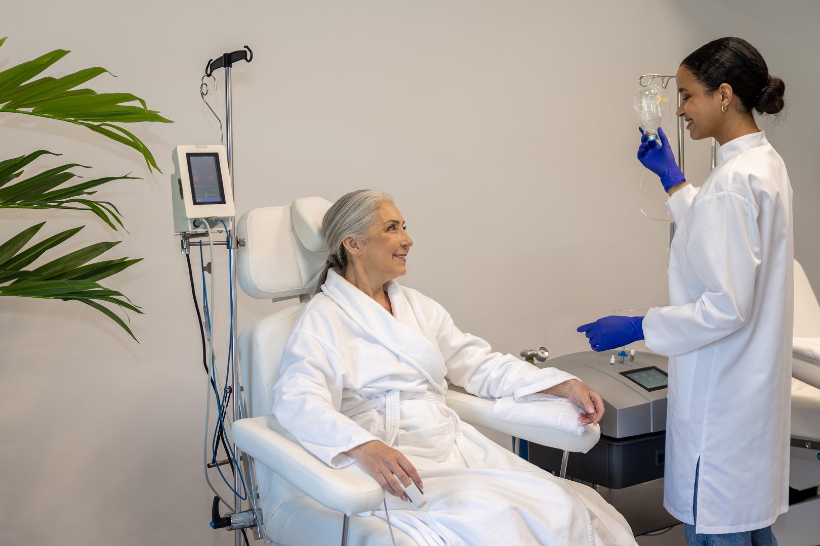 Professional doctor doing IV infusion for senior woman patient in beauty clinic.