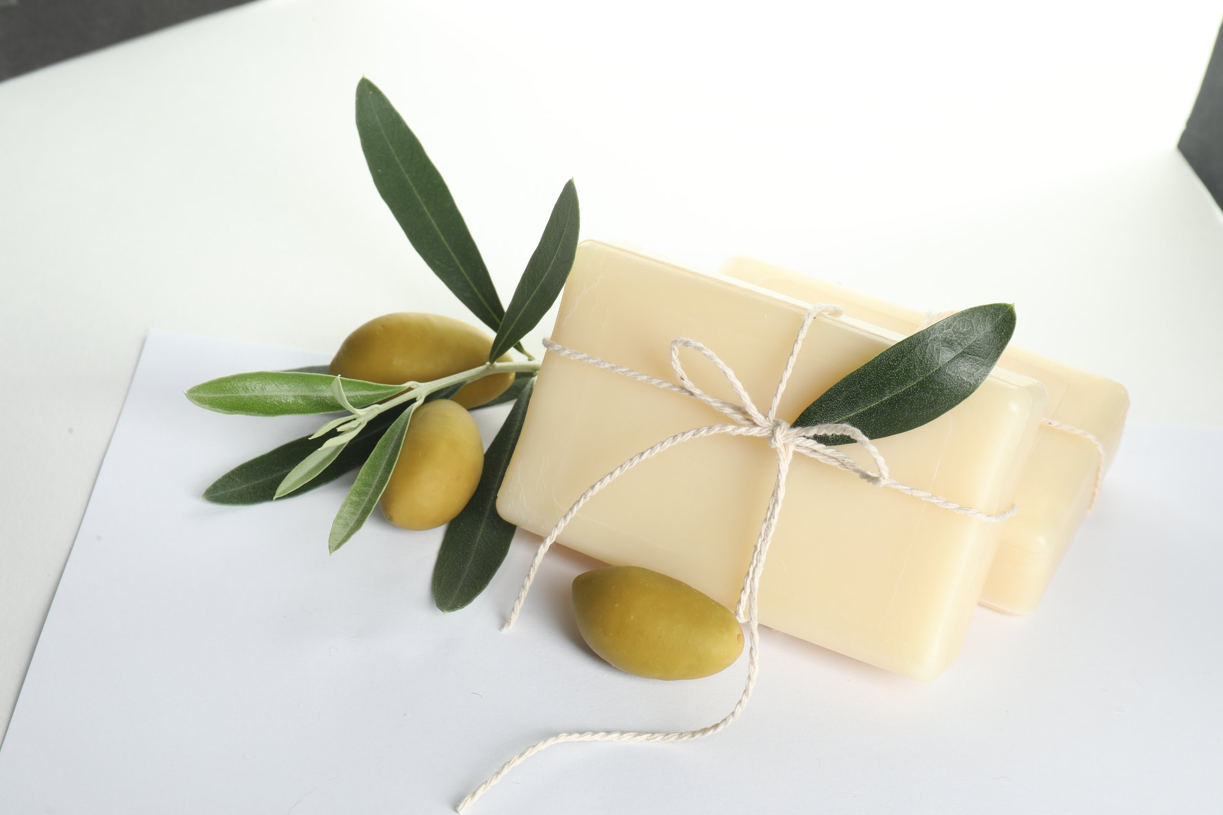 Handmade soap bars, olives and green leaves isolated on white
