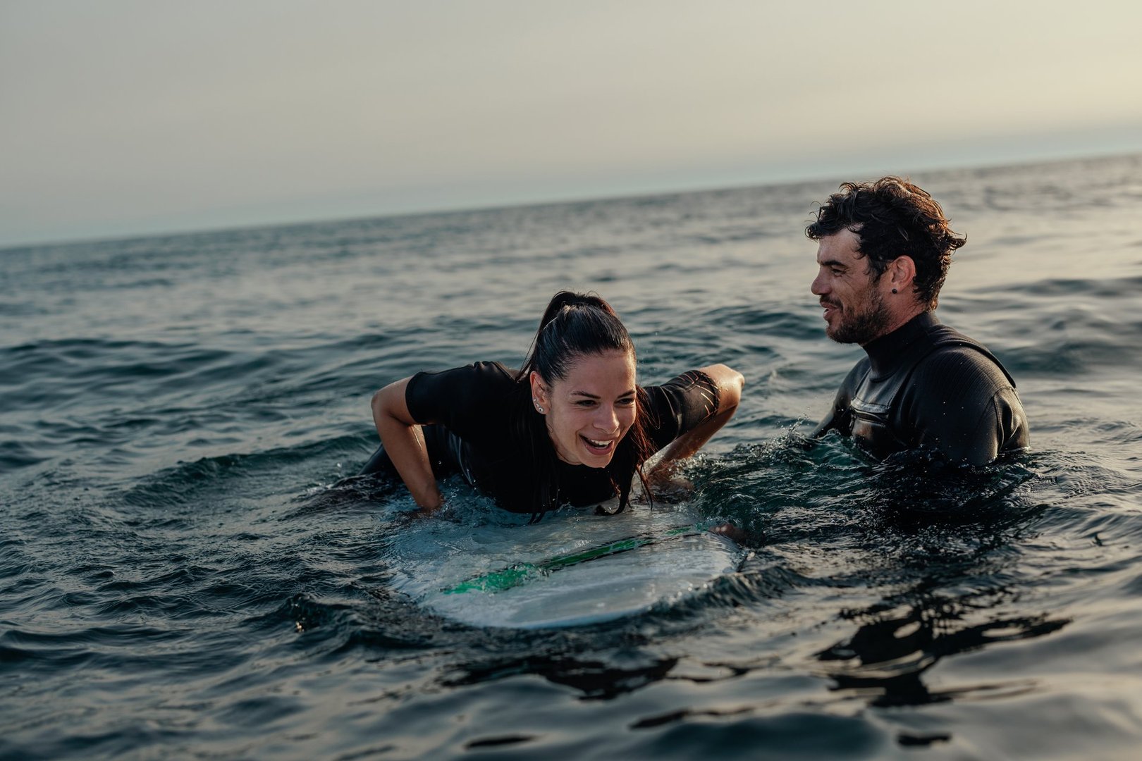 Instructor demonstrating to woman in surf class