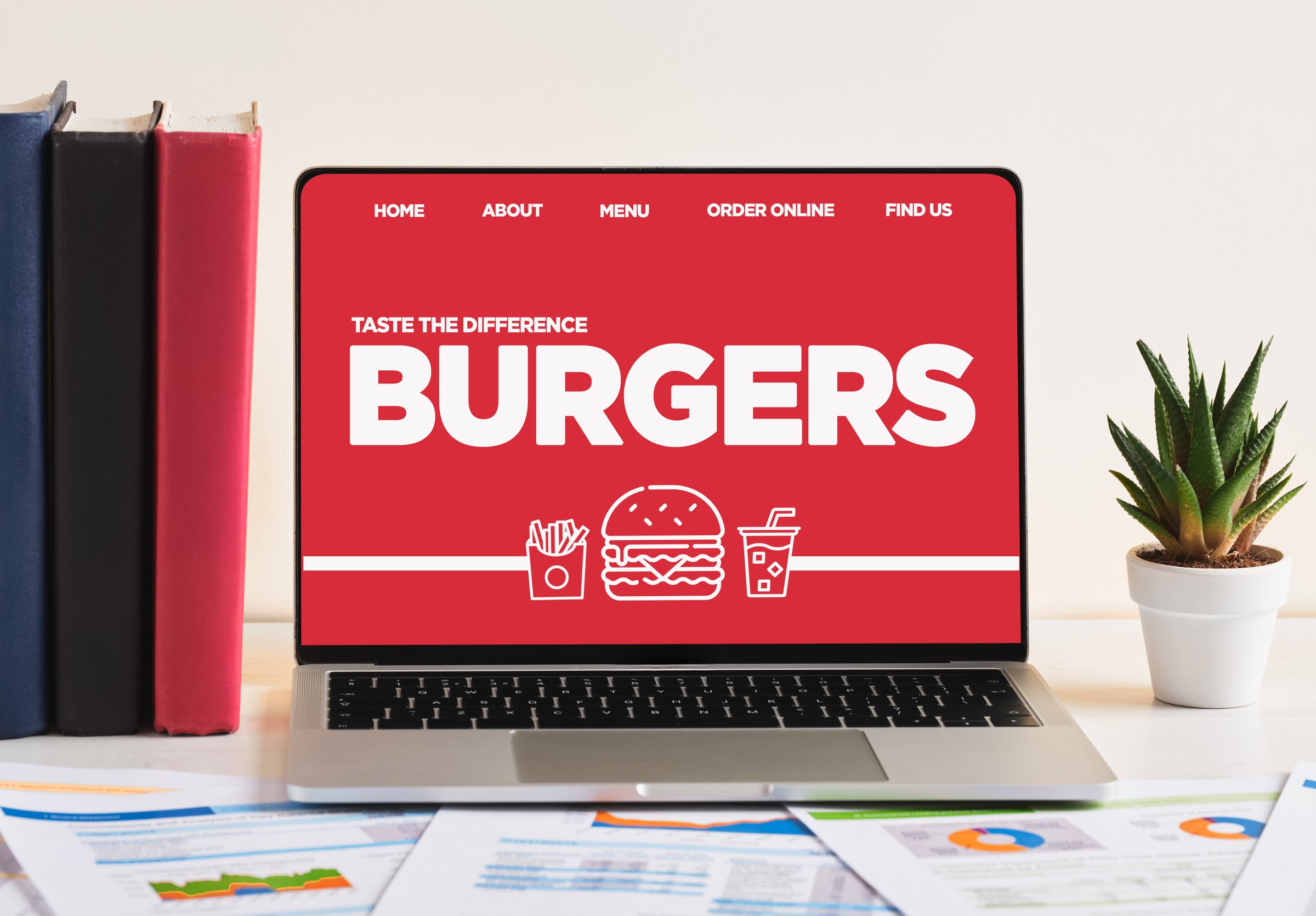 Laptop displaying burger website on a desk, promoting online food ordering