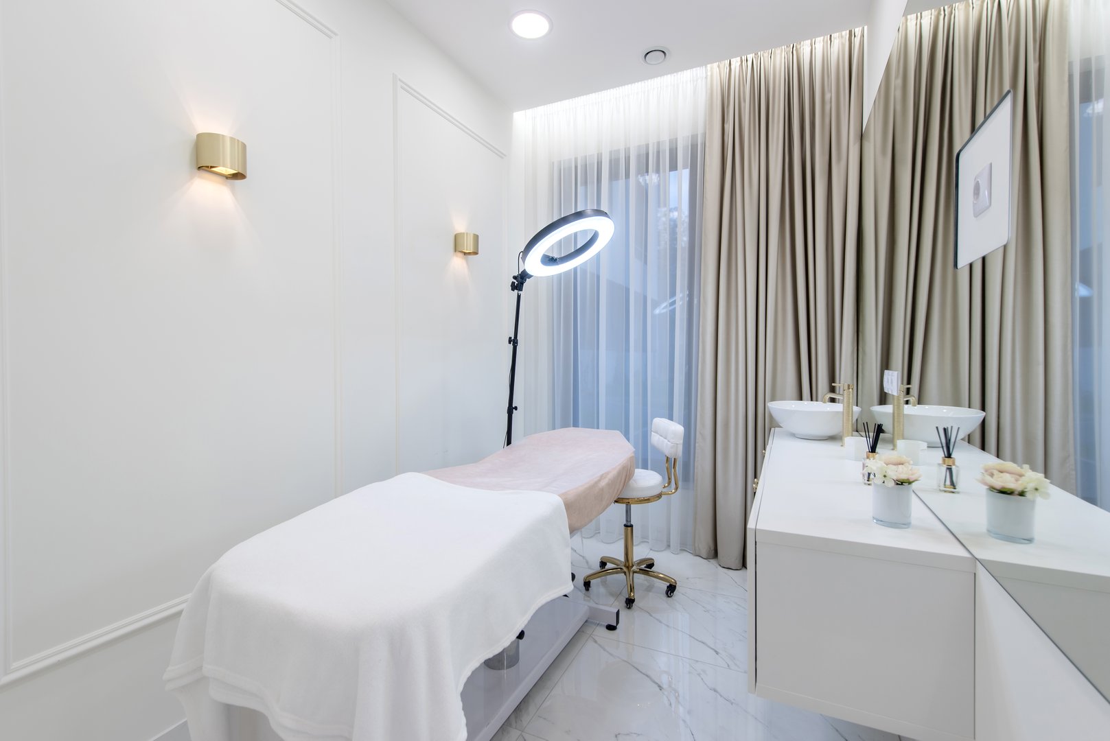 Elegant and minimalistic spa room interior with a treatment table, a ring light, and a serene ambiance.