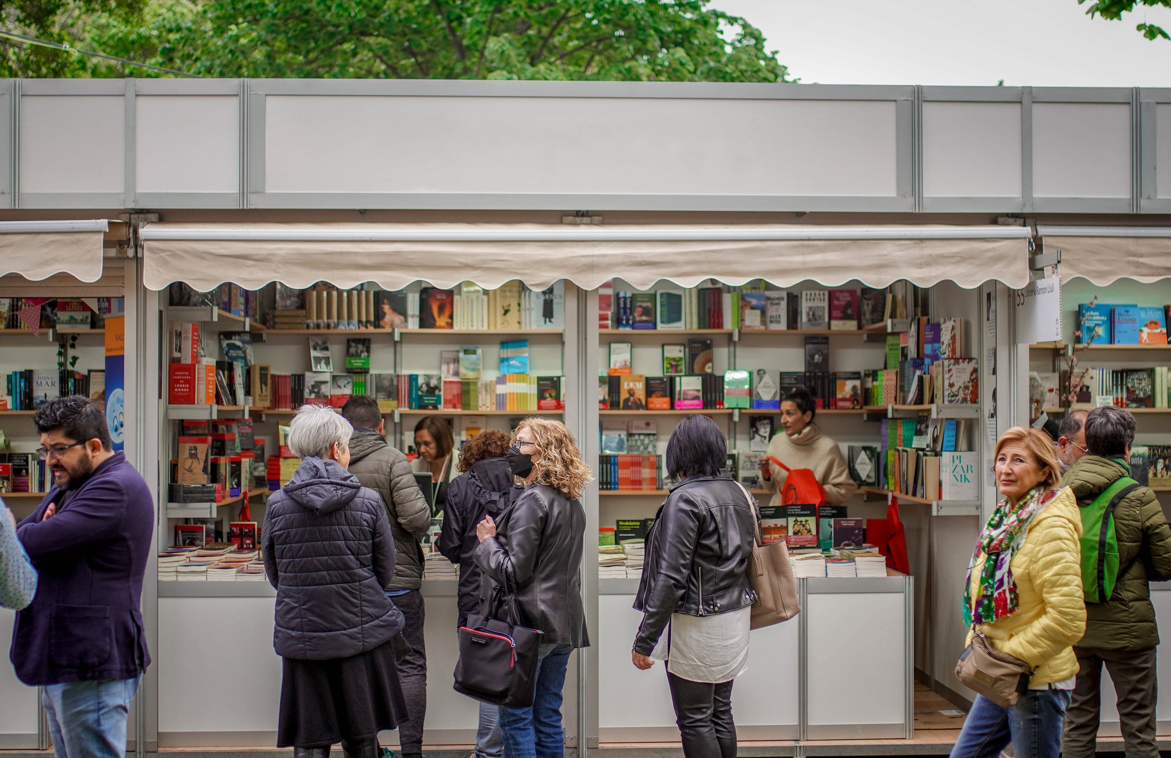 People Standing in front of a Book Shop Hoping to Find Goog Literature while Strolling on the Opening Day of the Book Fair in a Park