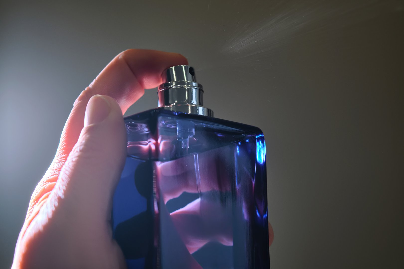 Perfume spray in a violet bottle on a dark background