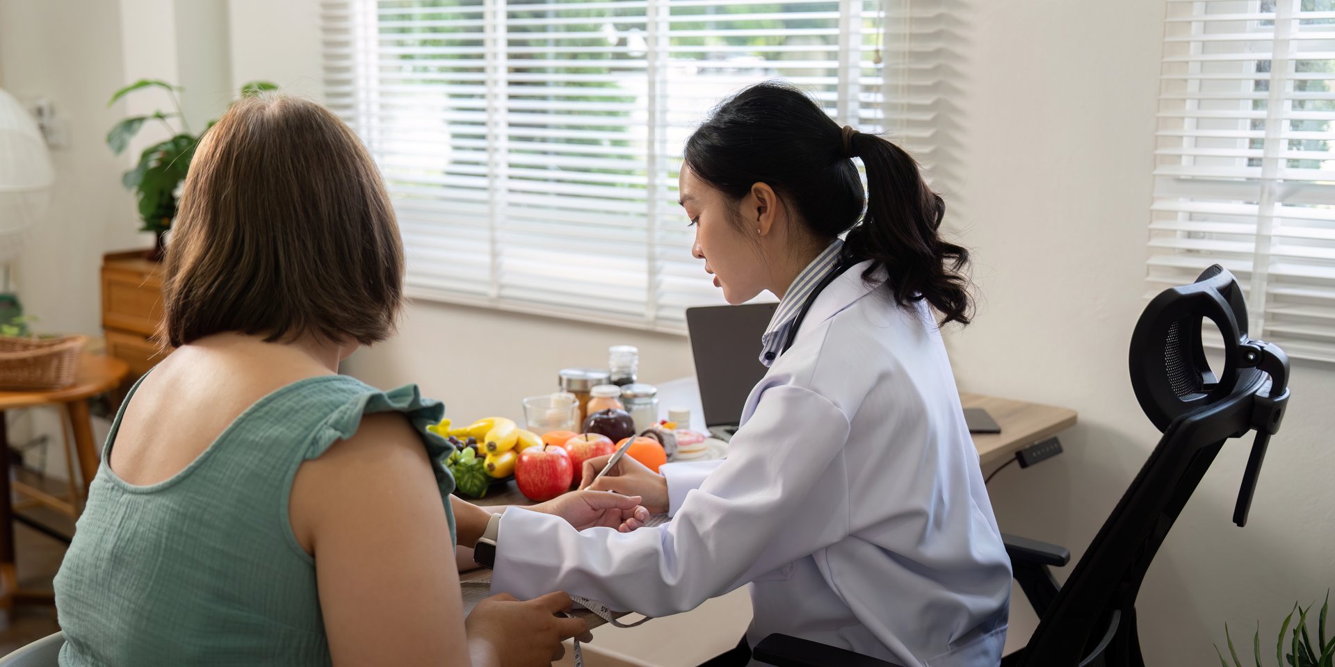In a comforting environment, a nutritionist is seen advising a client on a balanced diet, showcasing fruits and healthy options to promote well-being.