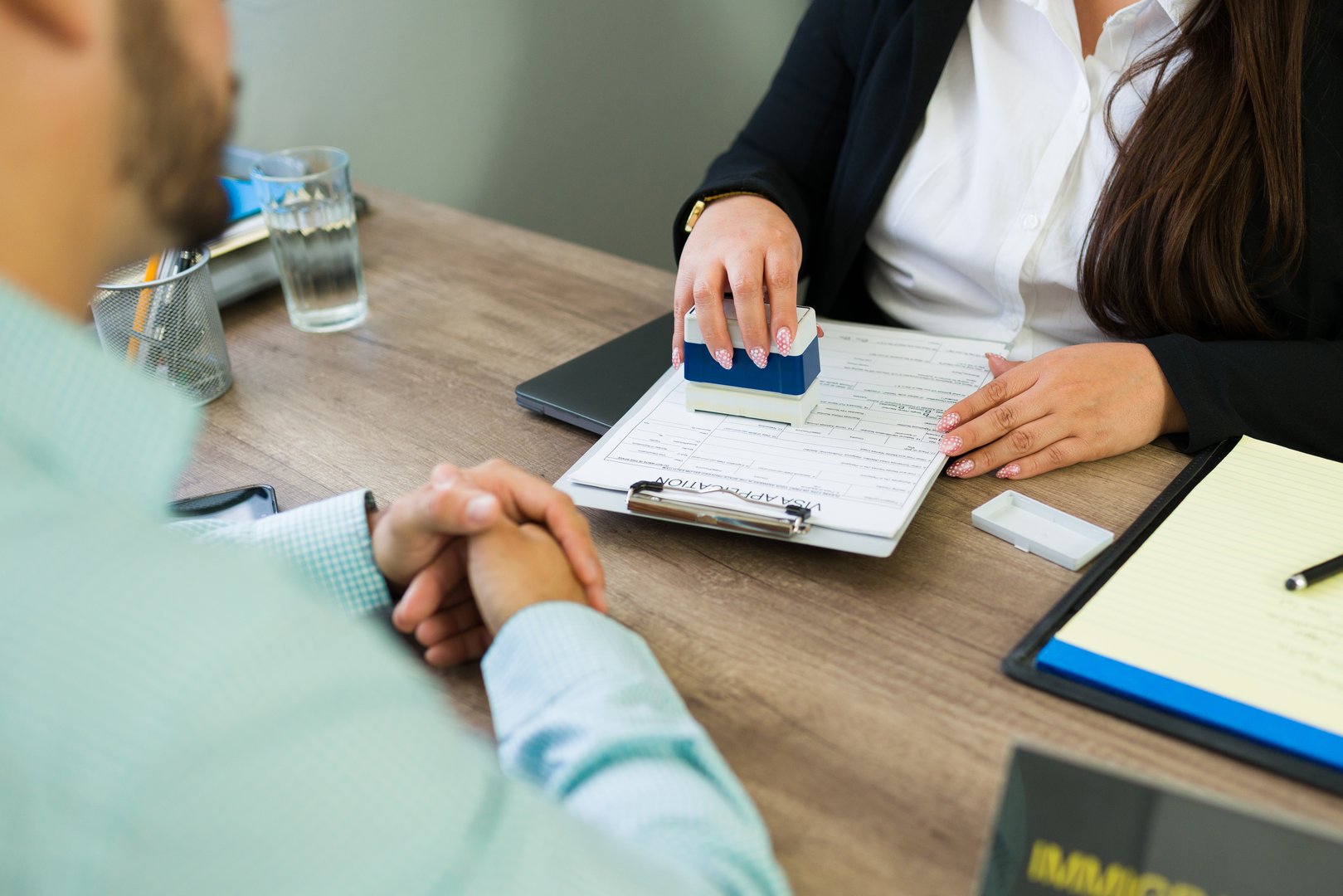 Immigration lawyer hand stamping a visa application or legal document for a client during a consultation in office