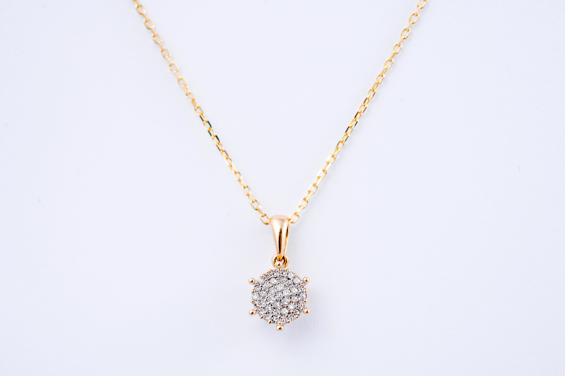 Elegant gold necklace with a diamond-studded pendant on a white background.