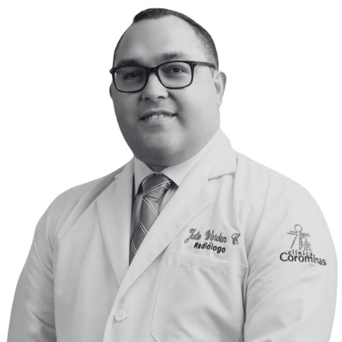 Man in a white lab coat with glasses, embroidered with name and Radiology, standing against a plain background.