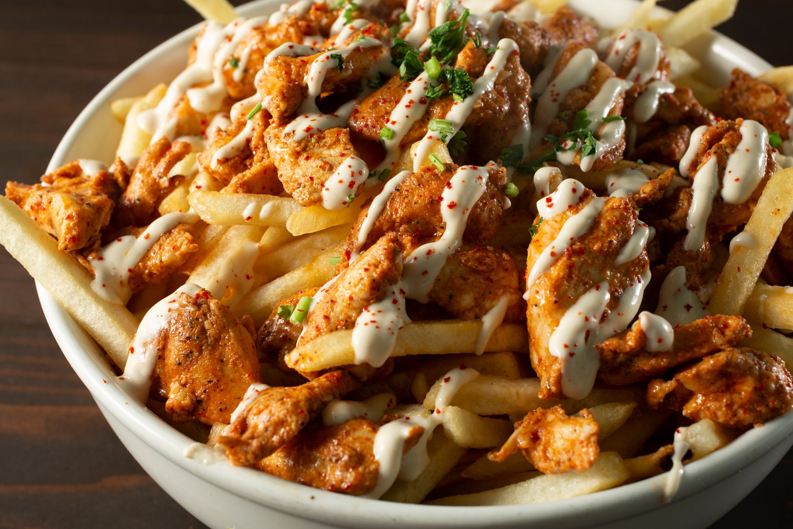 A closeup view of a bowl of chicken shawarma fries.