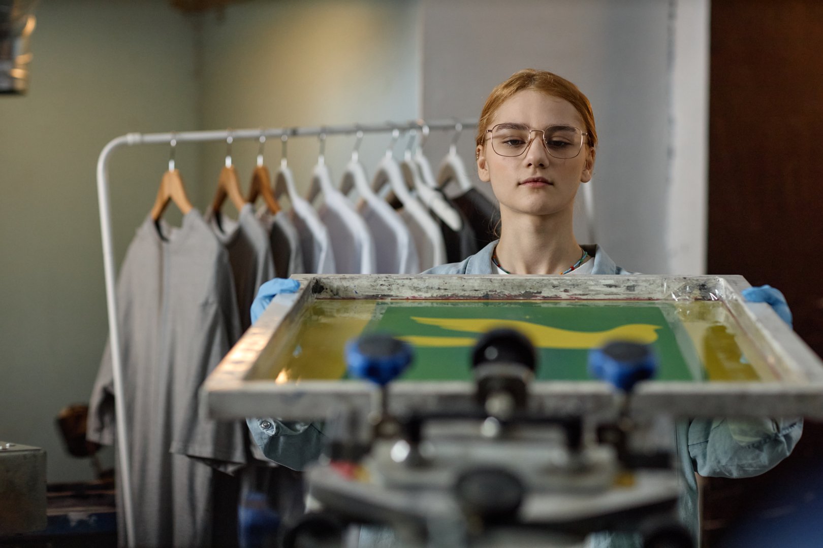 Screen printing machine operator crafting custom apparel