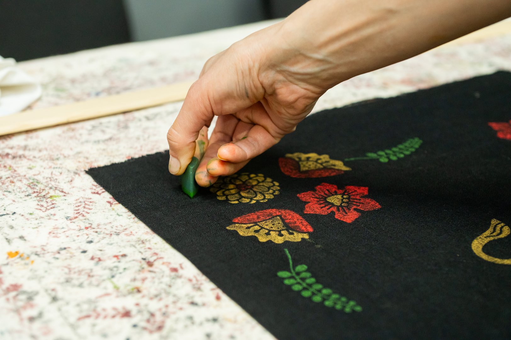 Hand block printing on fabric with bright floral patterns.