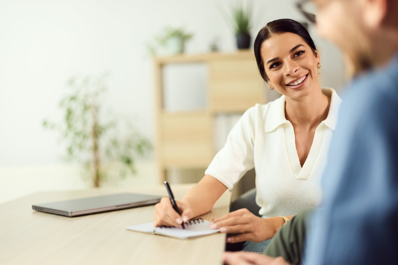 Friendly woman engaging in a professional meeting, writing notes in a cozy office.