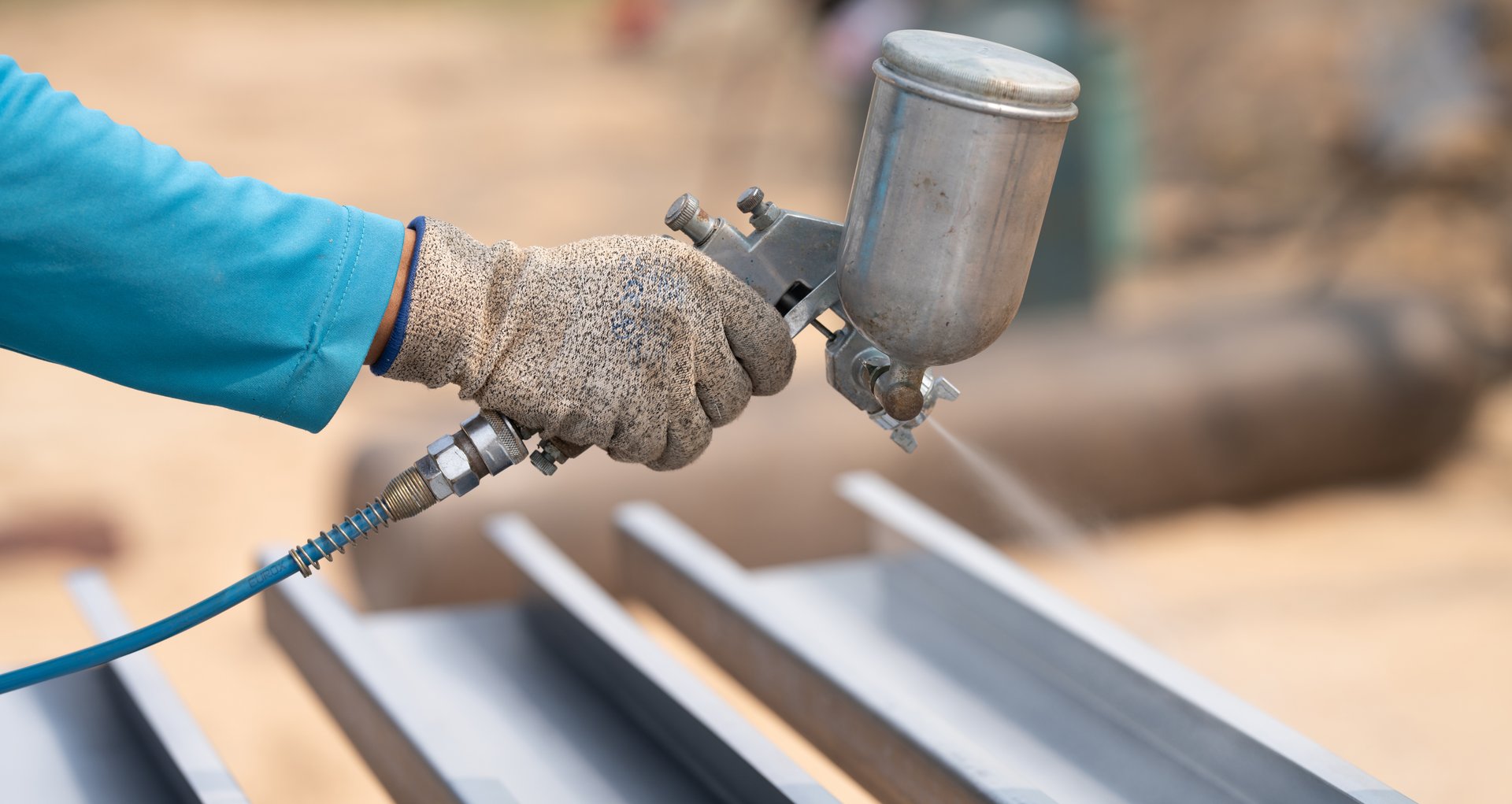 Construction worker painting metal structure surface coating with a spray gun at construction site. Metal corrosion and rust protection. Industrial precision. Protective coating to a metal structure.