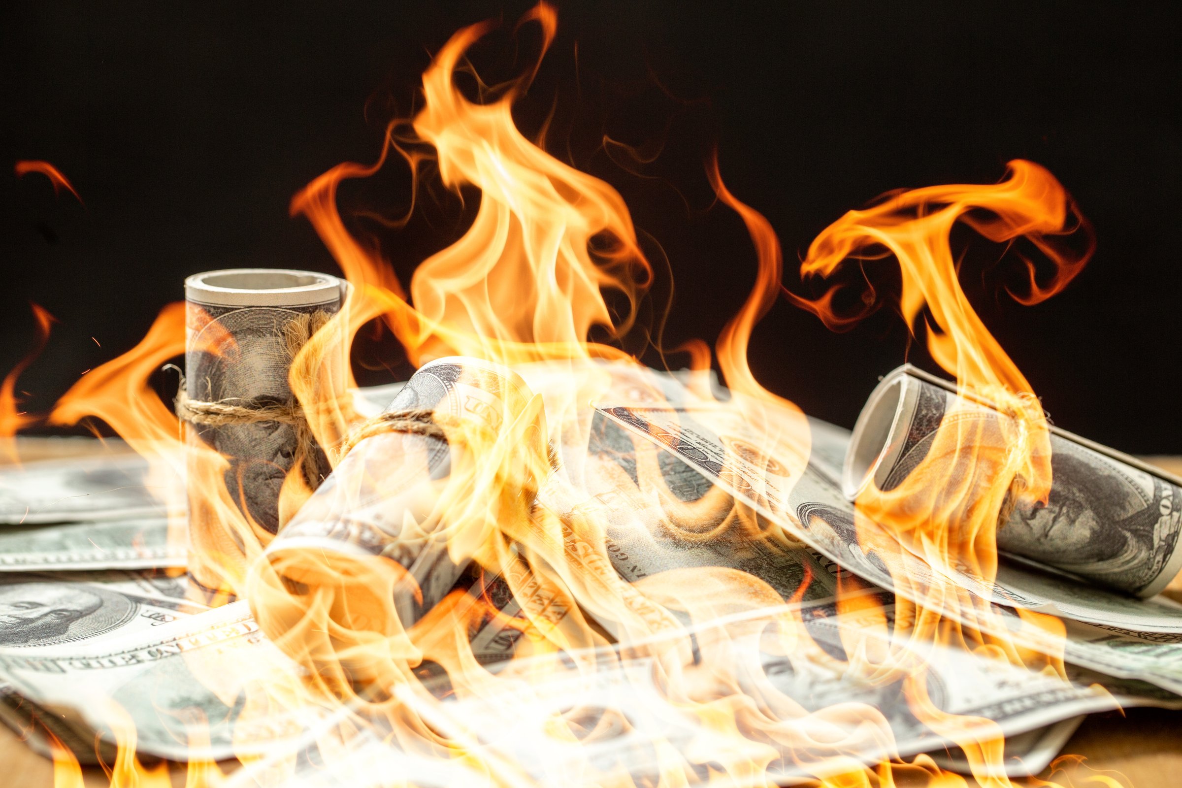 A stark visual representation of inflation, showing US dollar banknotes engulfed in destructive flames against a dark background. This powerful image conveys the concept of rapidly losing purchasing power, financial crisis, economic collapse, and the burning away of savings. It's ideal for illustrating articles on monetary policy, economic downturns, currency devaluation, and the challenges faced by individuals and businesses in an inflationary environment.