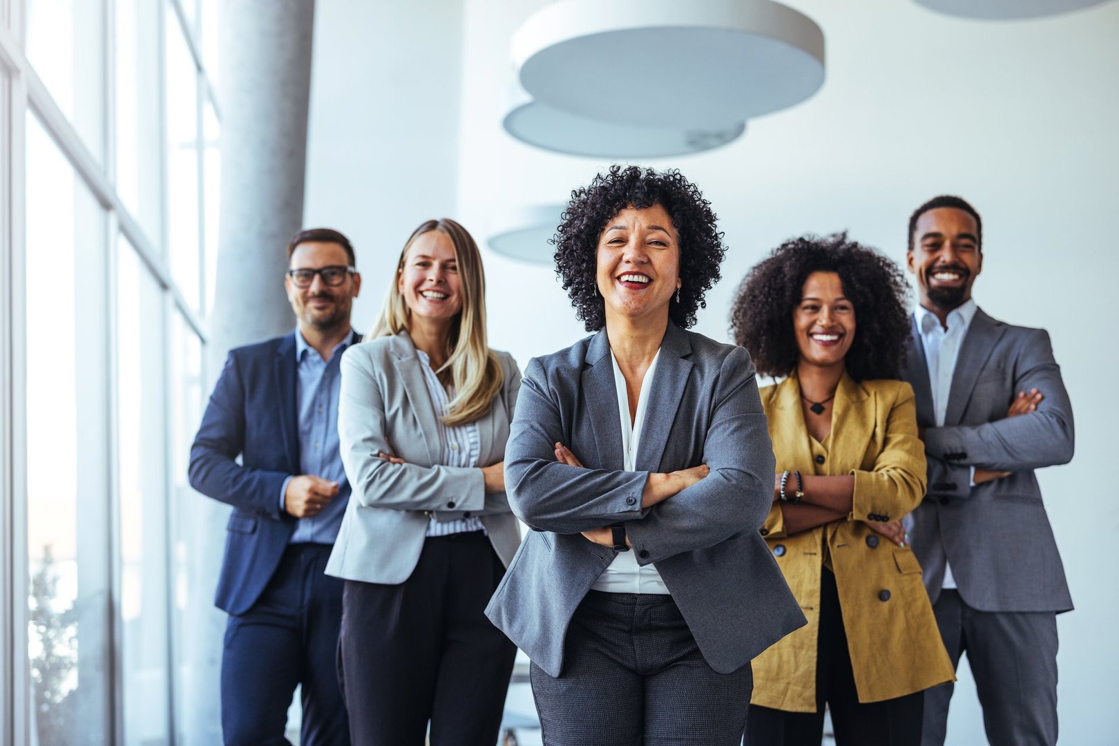 A diverse group of business professionals smiling confidently in a modern office environment. Their teamwork and cohesion portray leadership, unity, and professionalism, symbolizing success in diverse corporate settings.