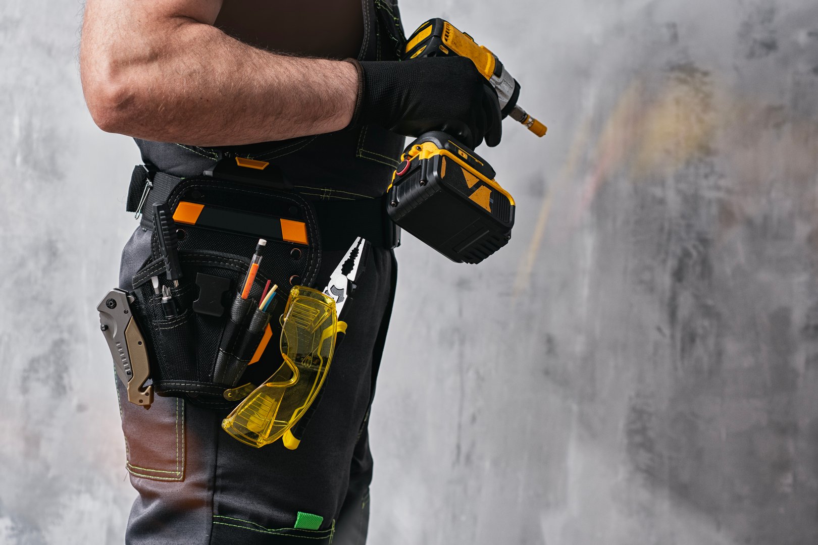 Uniformed construction worker holding a yellow colored cordless screwdriver