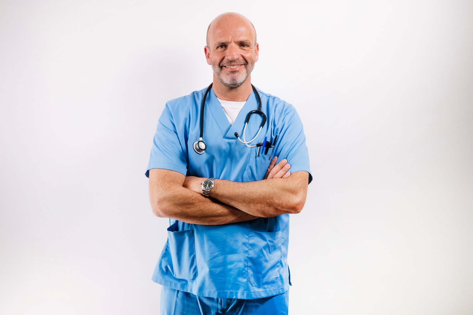 A Doctor in light blue gown looking at camera in studio.