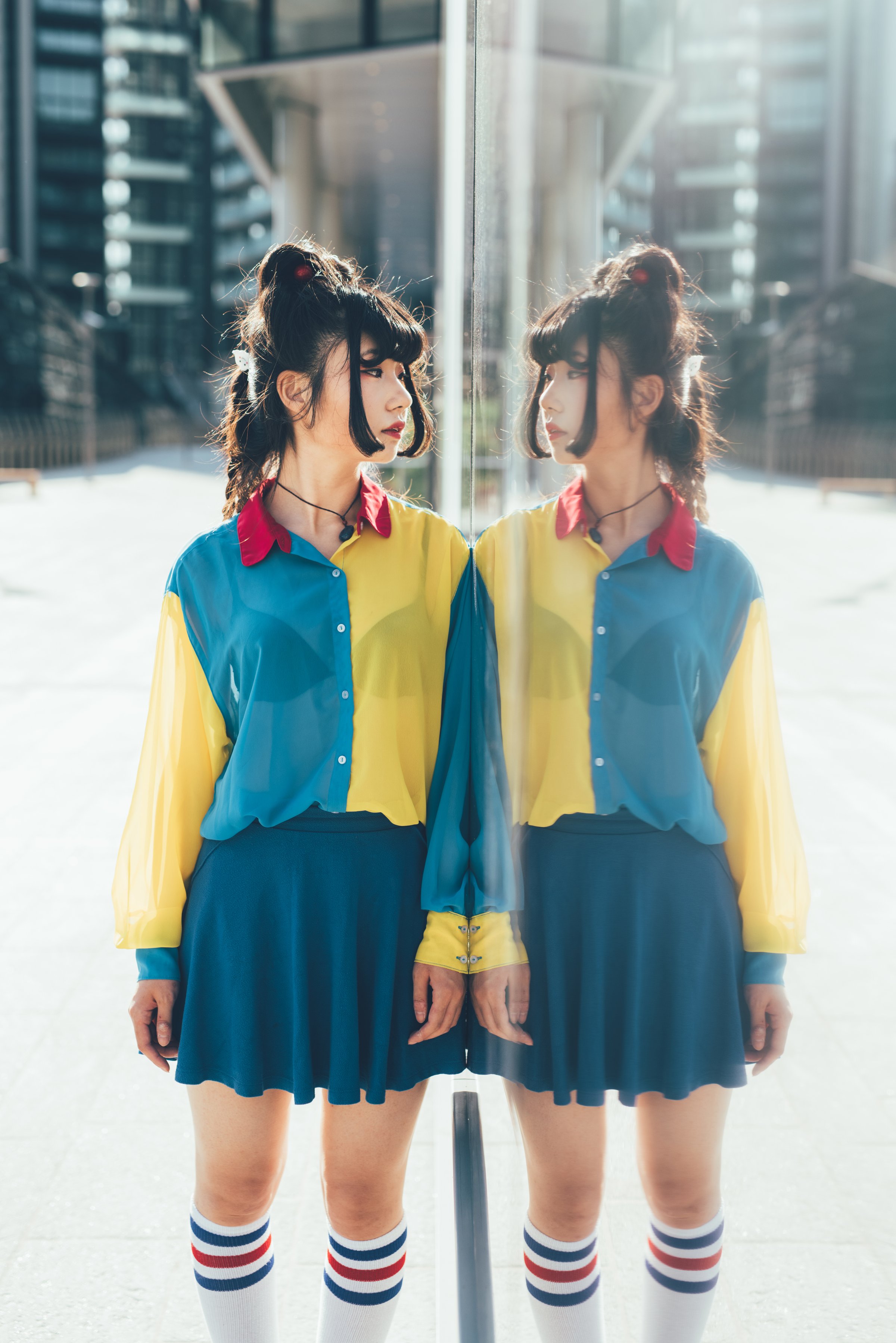 Young beautiful nonconformist asiatic woman posing outdoor in the city, looking at herself in the mirror pensive - thoughtful, serious, eccentric concept