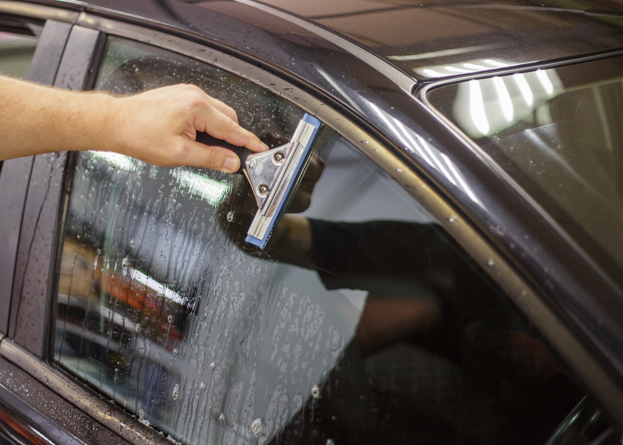 A series of tinting car windows. Installation of tinting film on the car glass. Specialist in the installation of tinting film in the process of work.