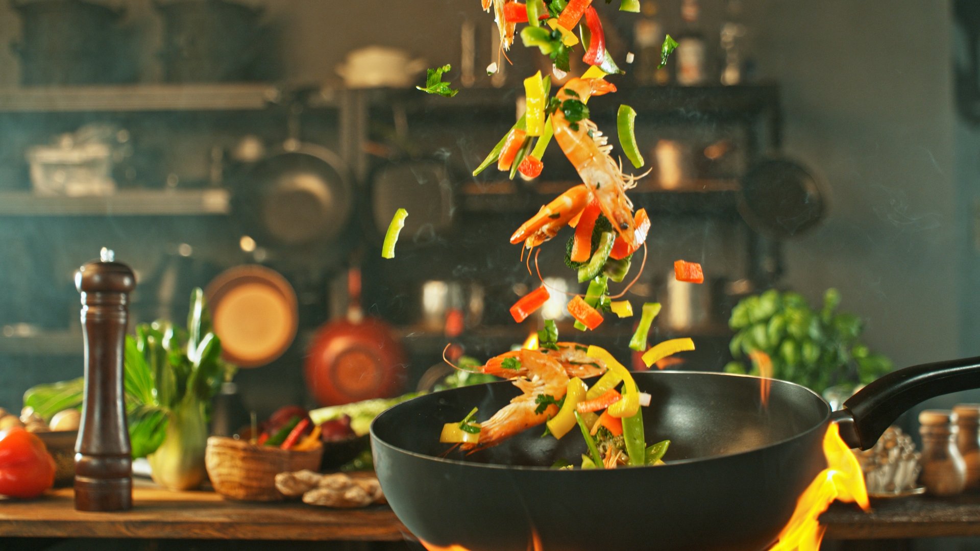 Freeze Motion of Wok Pan with Flying Ingredients in the Air. Kitchen on Background.