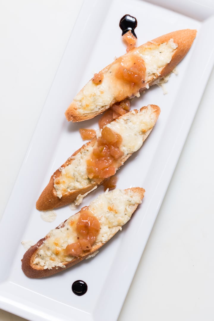 Toast bruschettes topped with cheese and quince jam on white background
