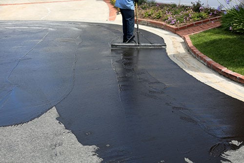 Seal coating application on asphalt driveway