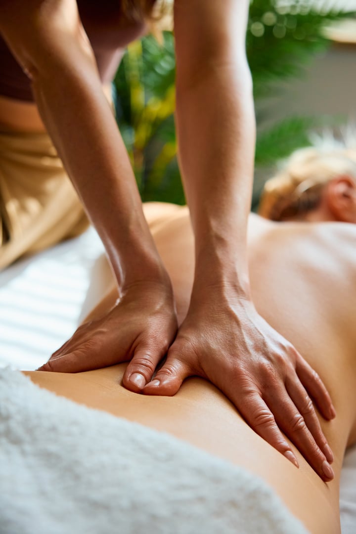 Closeup of masseuse hands massaging female patient