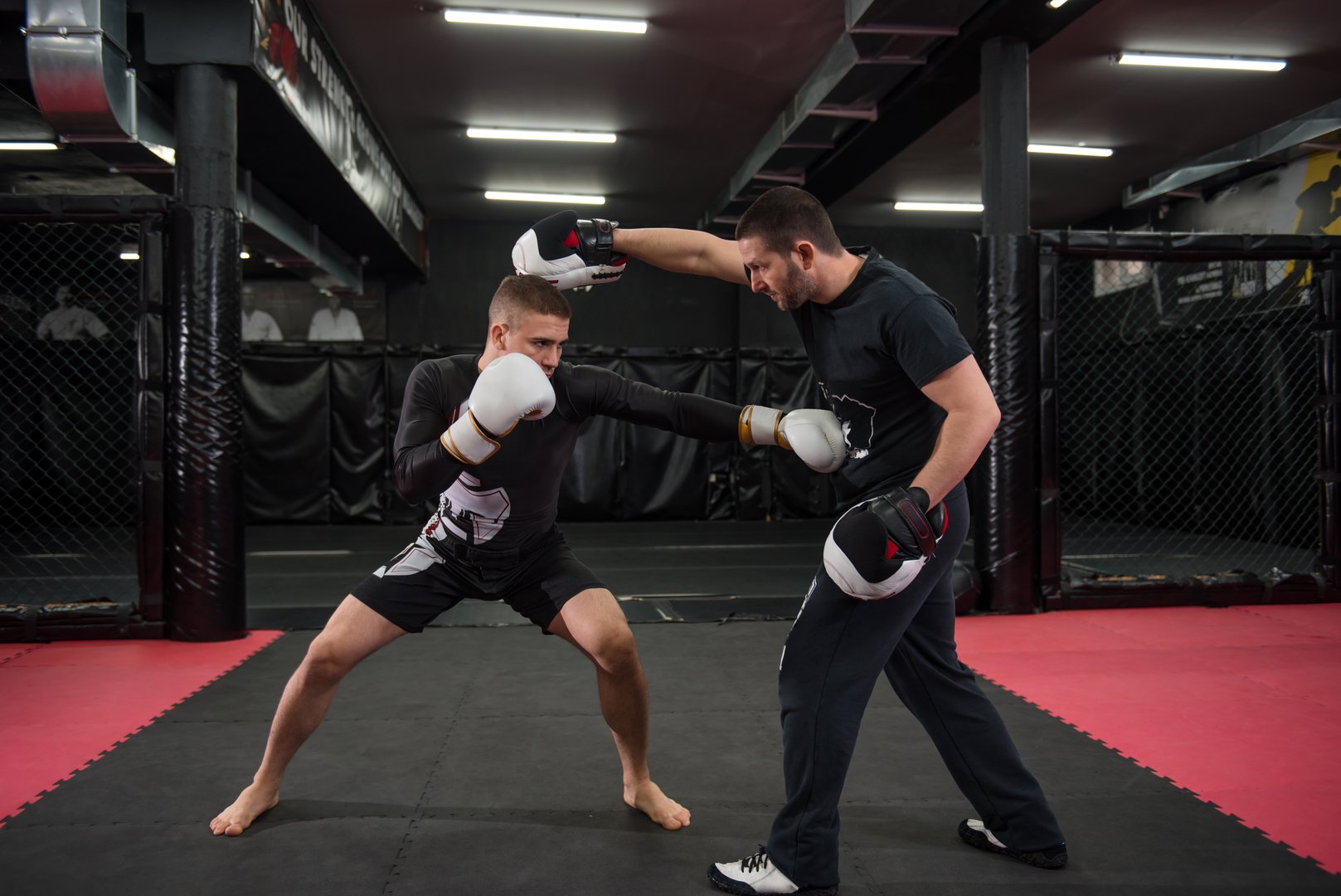 Caucasian fighter at kickboxing training practicing punching, kicking and sparring with his trainer.