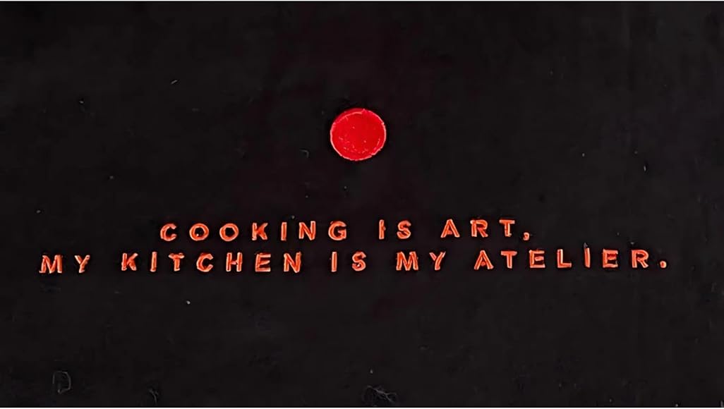 Black background with red text: "Cooking is art, my kitchen is my atelier." Red circle above the text.