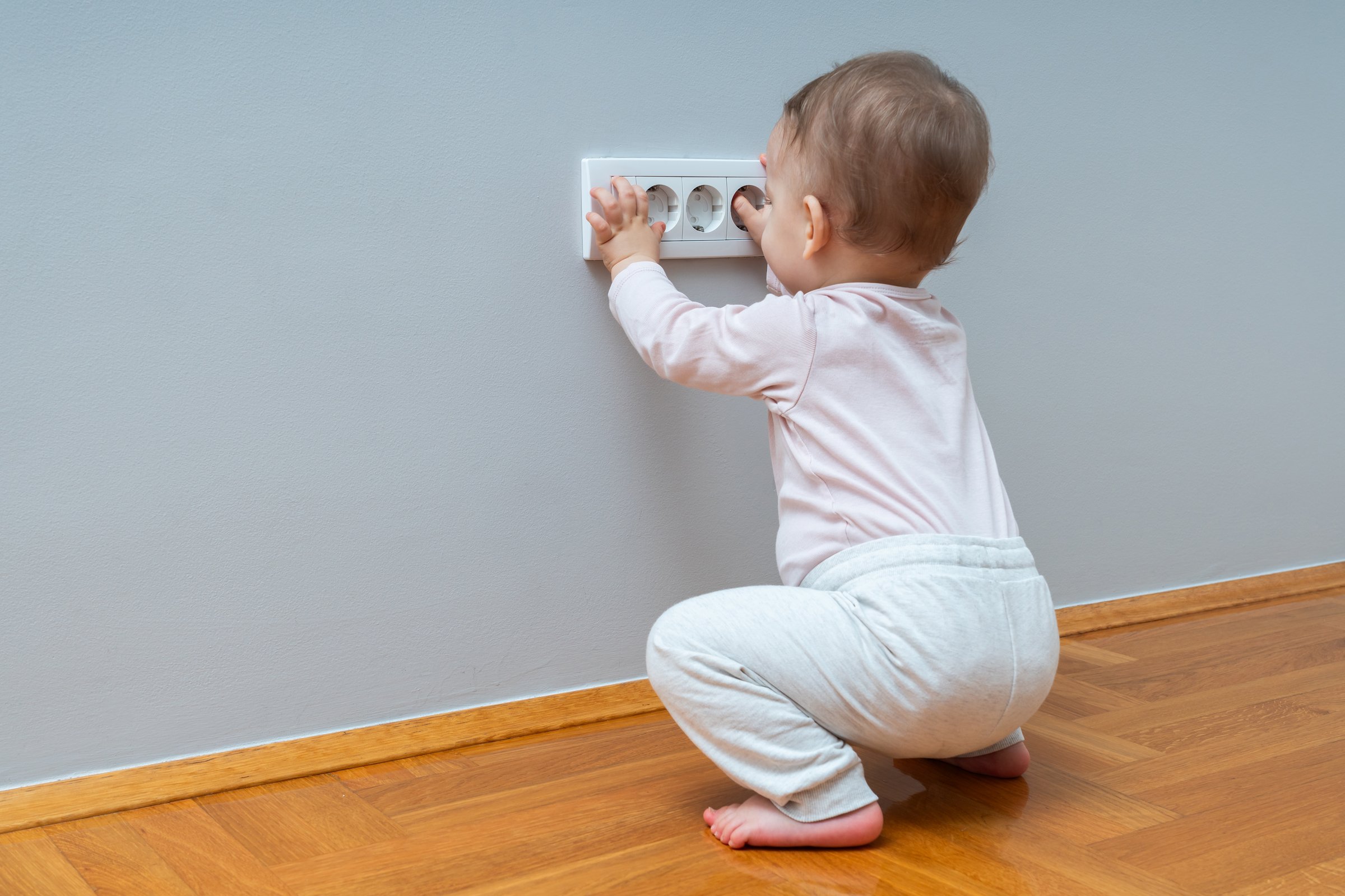 Baby playing with electrical outlet with safety plug