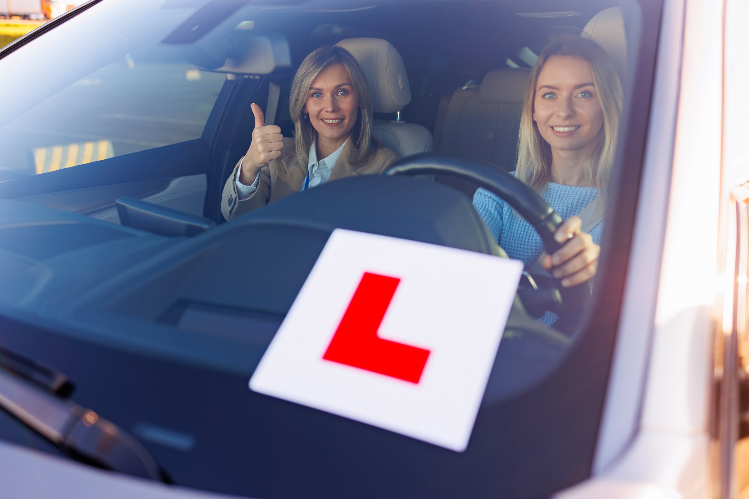 Learner Driver with Instructor Showing Thumbs Up in Vehicle