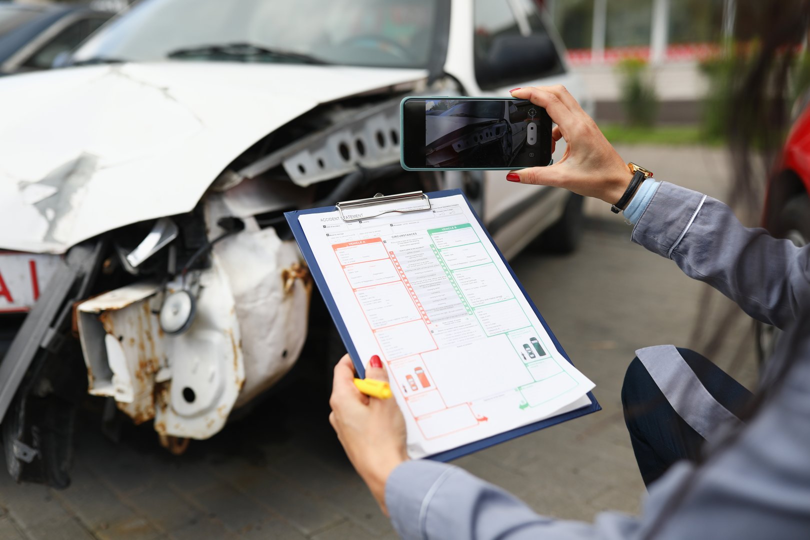 Insurance agent takes pictures of crashed car on his smartphone and fills out the insurance. Insurance agent services concept