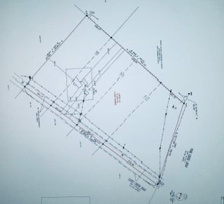 A technical blueprint of a slanted rectangular plot with measurements, angles, and labeled lines indicating construction details.