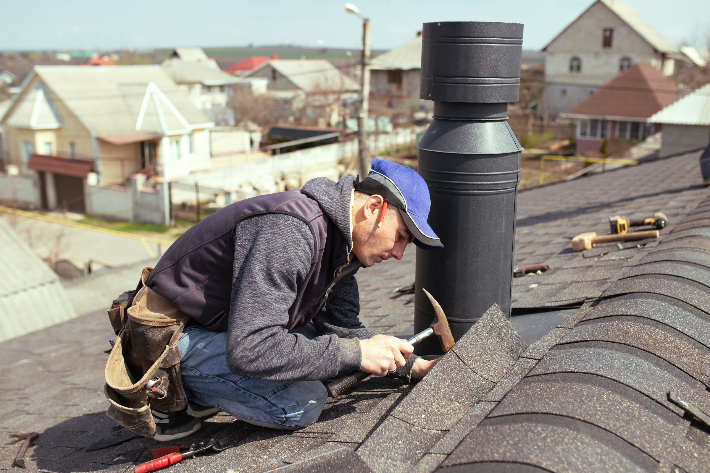 Professional roofer repairing roof with hammer
