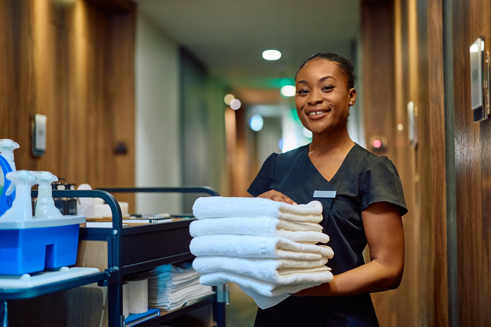 Happy African American woman working as chambermaid in a hotel and looking at camera. Copy space.