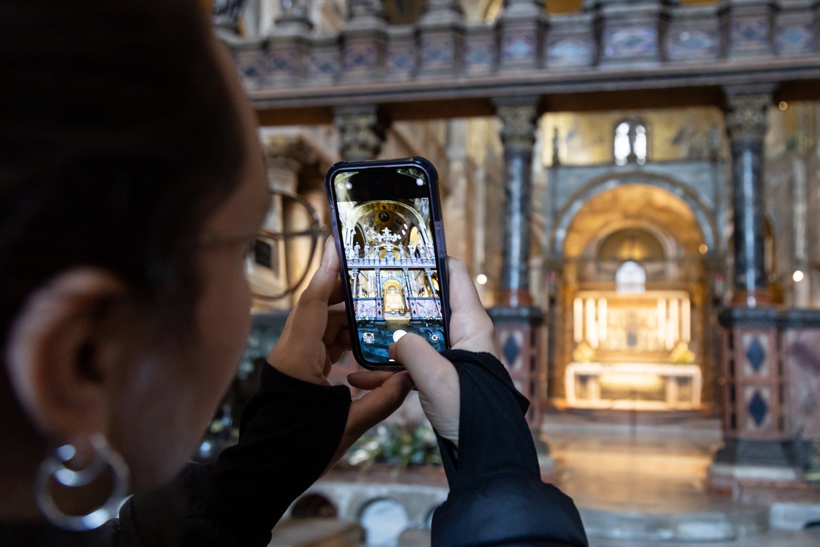 A female tourist taking photos with phone inside the Basilica di San Marco (Saint Mark's Basilica) in Venice; Italy