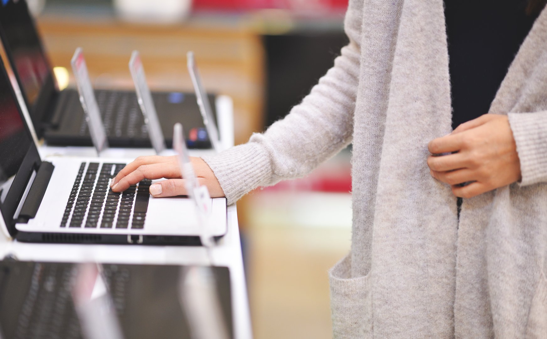 Woman chooses the laptop in electronics store